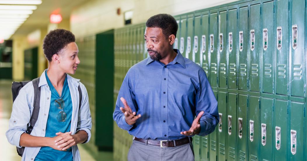 Teacher and high school student walking in hallway
