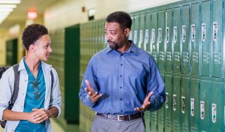 Teacher and high school student walking in hallway