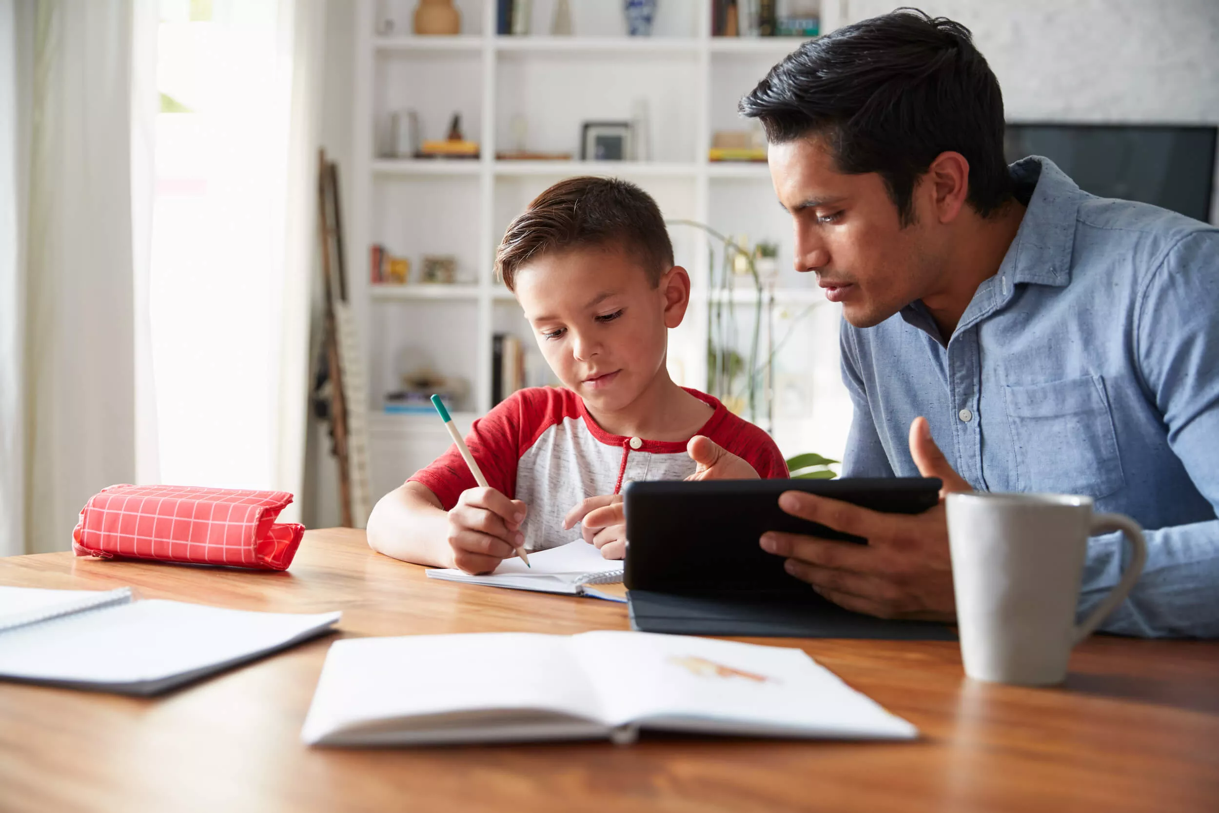 Teacher helping elementary age child with homework at table